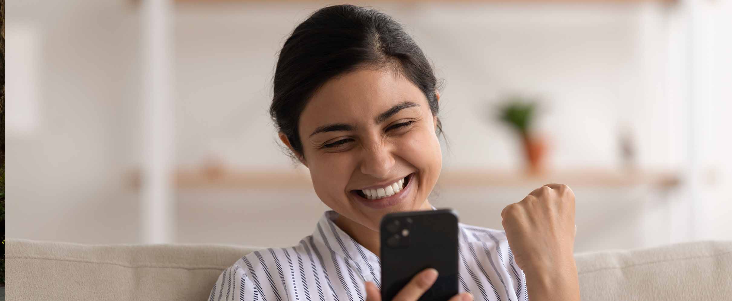 woman looking very ecstatically at a mobile phone screen